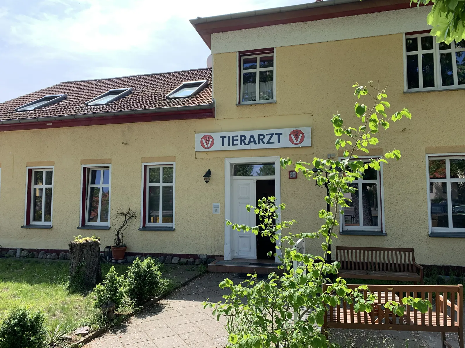Die Tierarztpraxis Kammbach von vorn, gelbes Haus mit Tierarzt-Schild